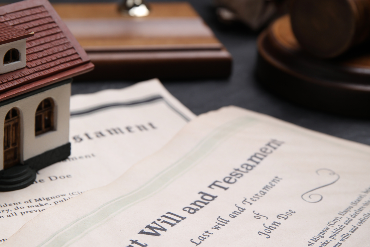 Will and testament form with a mini house on the paperwork; probate concept