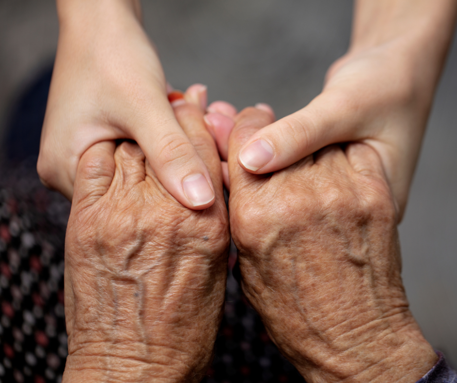 a set of elderly hands are being held by a pair of young hands in a caring way