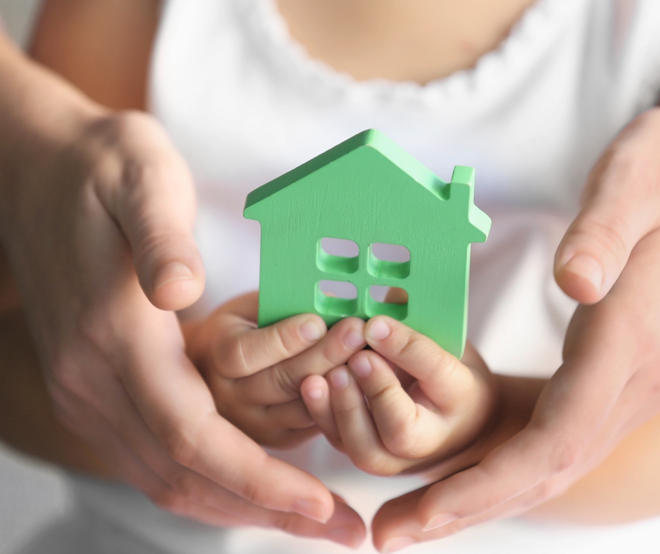 Child and adult person holding figure in shape of house, closeup. Adoption concept